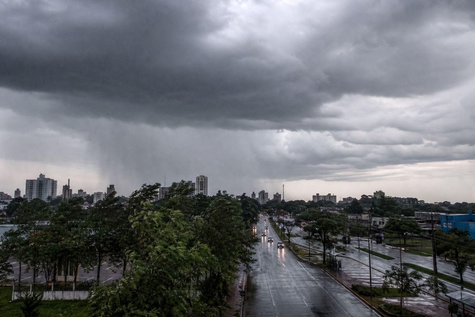 Nuvens escuras avançam sobre uma cidade durante chuva